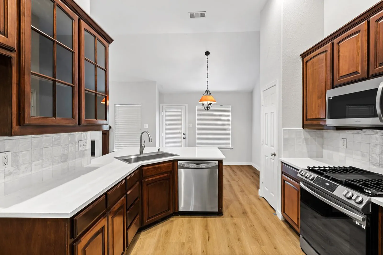 Kitchen at Biscayne in Frisco after the pre-sale refresh: existing cherry cabinets with new white quartz counters, subway tile backsplash, and stainless appliances
