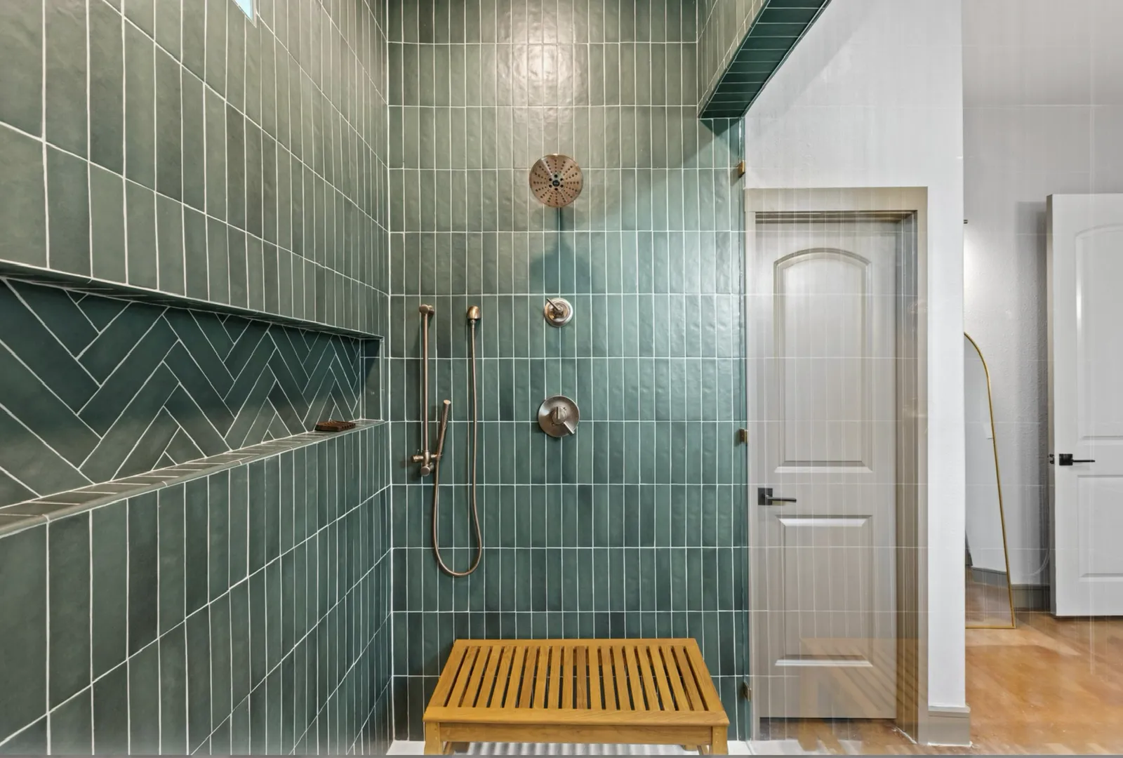 Herringbone tile niche and brass fixtures in the Lake Breeze Dr. shower in McKinney