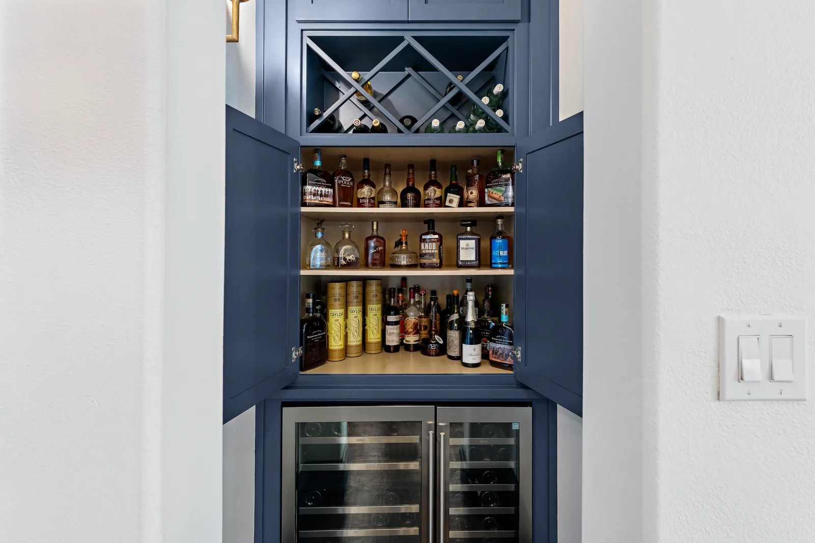 Navy bar nook with wine refrigerators and a wine rack at Revere Pl. in Lakewood, Dallas