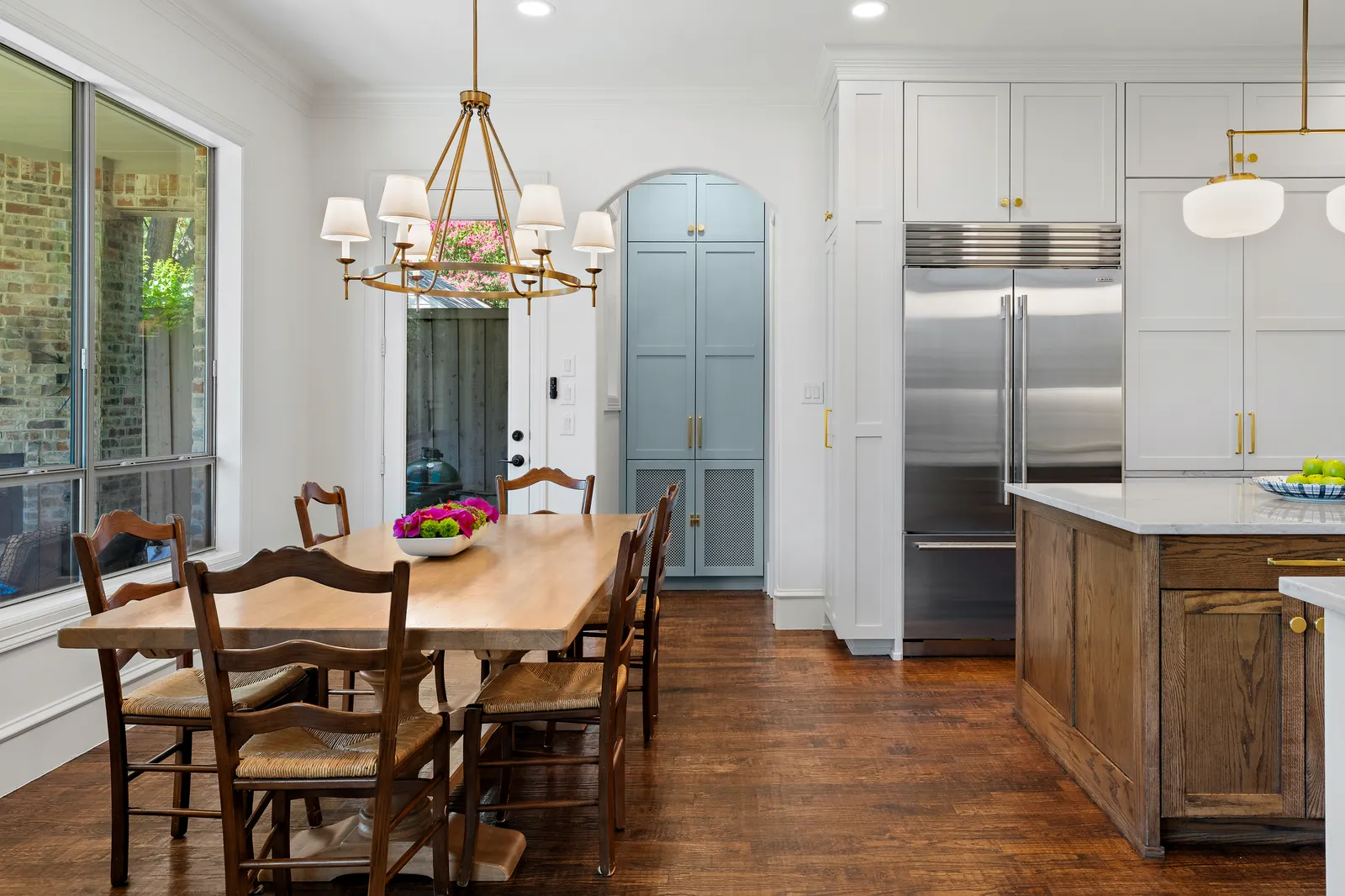 Kitchen at Revere Pl. in Lakewood, Dallas after Renovation Sells Dallas: white cabinetry, stained oak island, stone counters, brass hardware, and a light blue pantry behind an arched opening