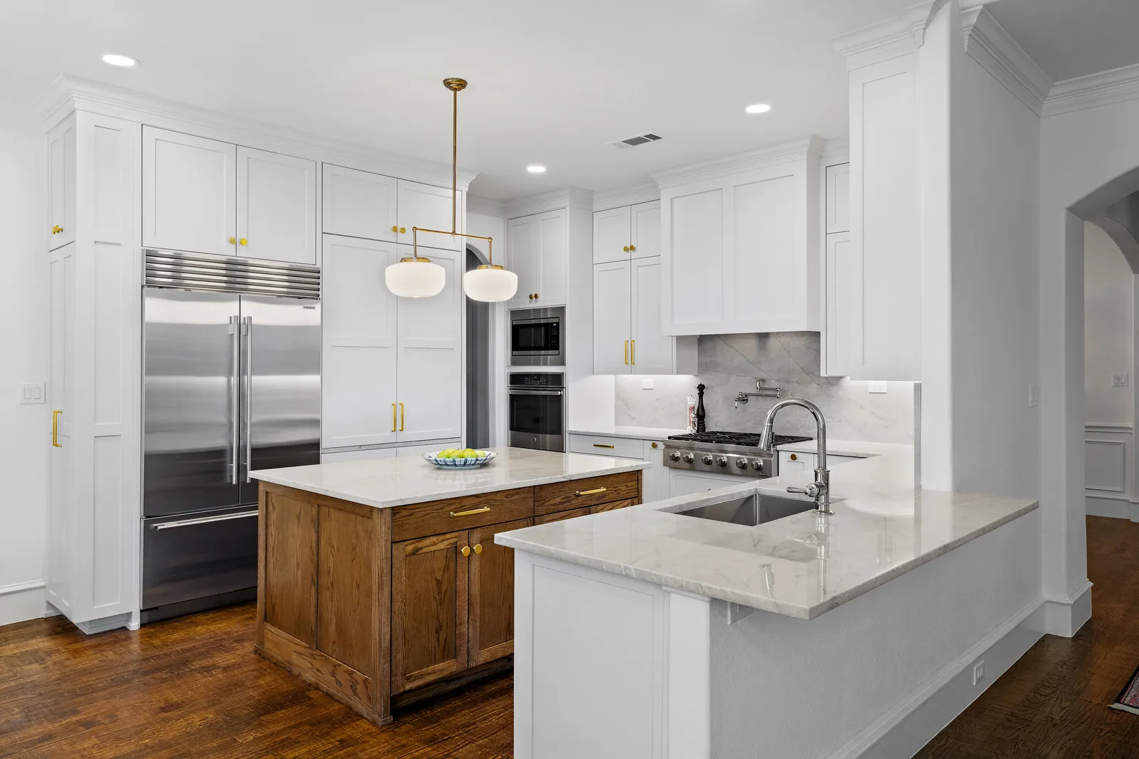 Wide view of the remodeled Revere Pl. kitchen in Lakewood: island with pendant lights, paneled refrigerator wall, and double ovens