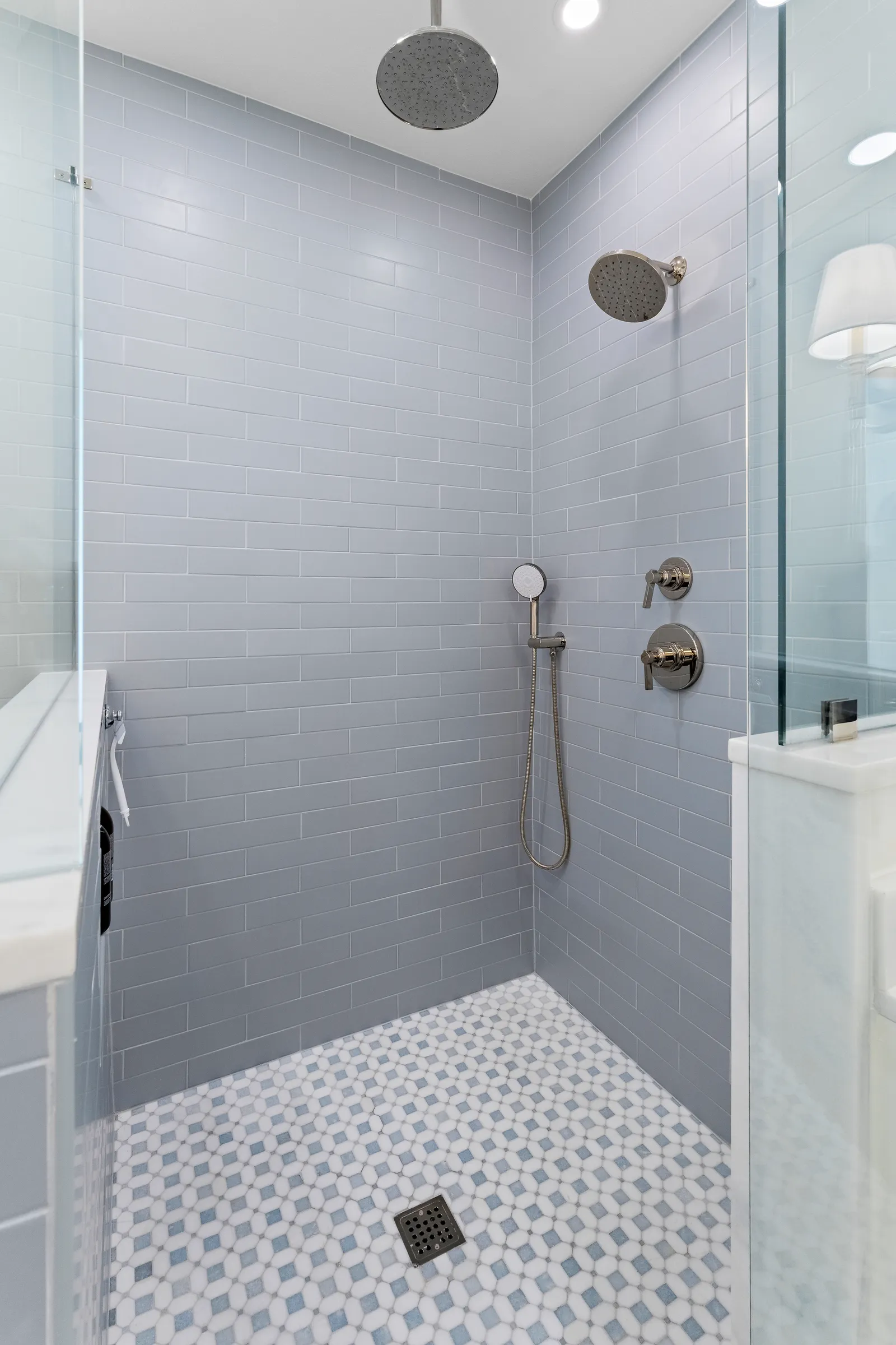 Gray subway-tile shower with rain head and mosaic floor at Revere Pl. in Lakewood