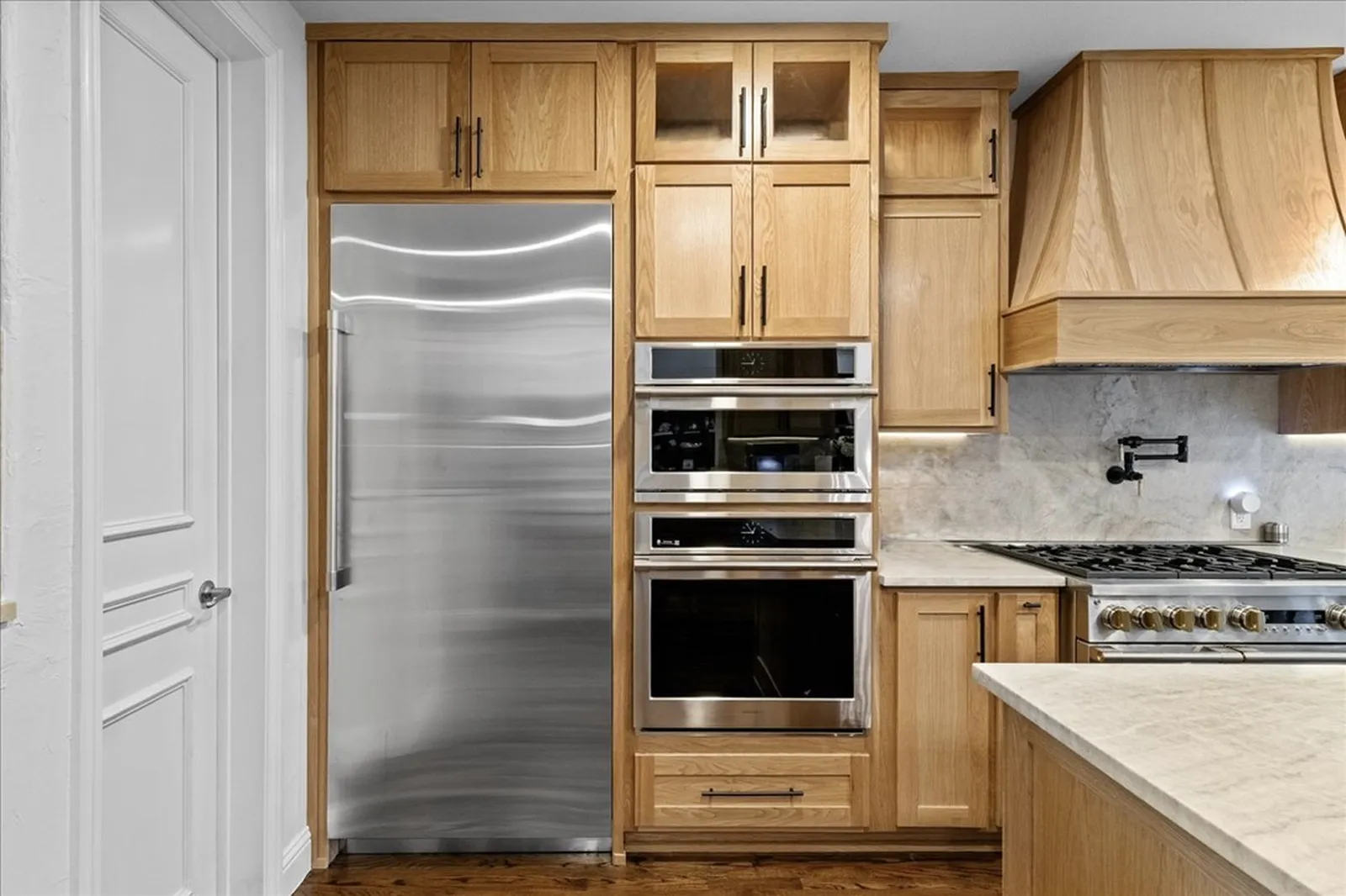 Paneled refrigerator, double ovens, and white oak cabinetry at Shady Point Dr in Plano after the remodel by Renovation Sells Dallas