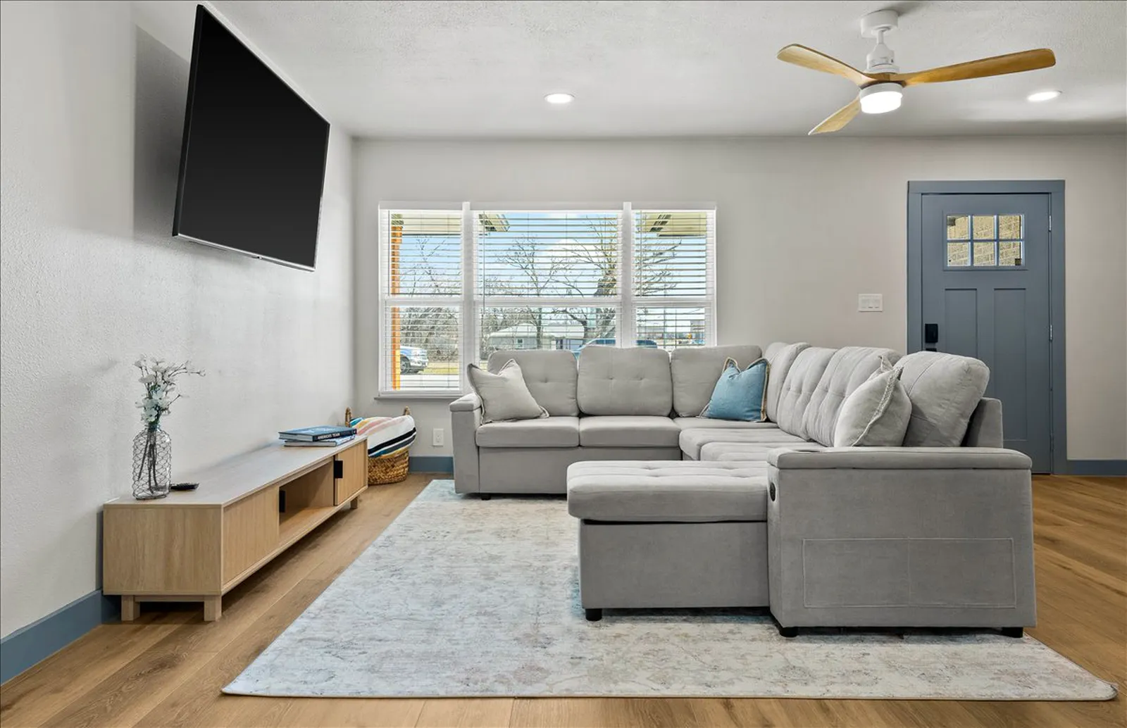Open living room with new plank flooring and a blue front door at Sherman St. in McKinney
