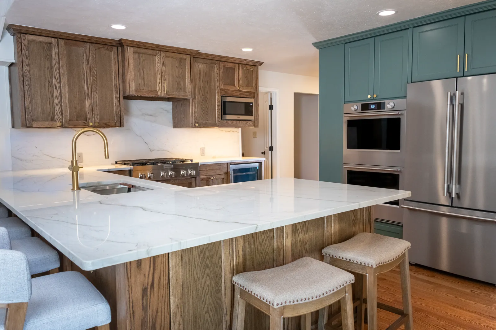 Remodeled kitchen at Vancouver Dr. in Preston Hollow: stained oak cabinets, quartzite counters, brass faucet, and a large island