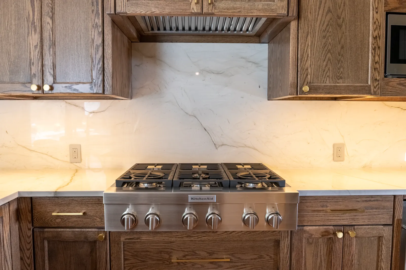 Range wall with marble backsplash and oak cabinetry at Vancouver Dr. in Preston Hollow